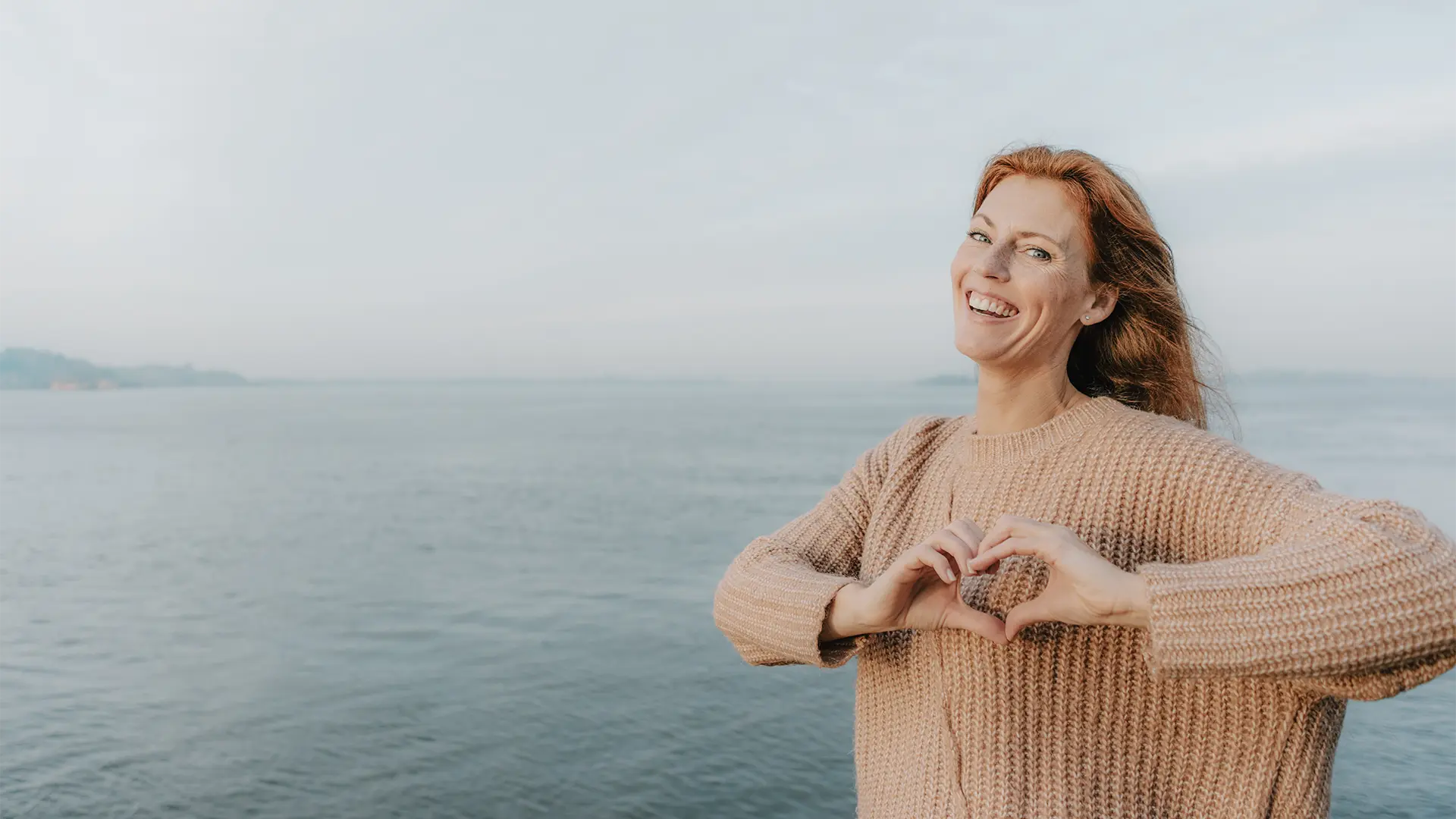 Natürliche Nahrungsergänzung für Herz, Kreislauf und Blutgefäße Lachende Frau formt mit ihren Händen ein Herz – Symbolbild für emotionale und körperliche Herzgesundheit.