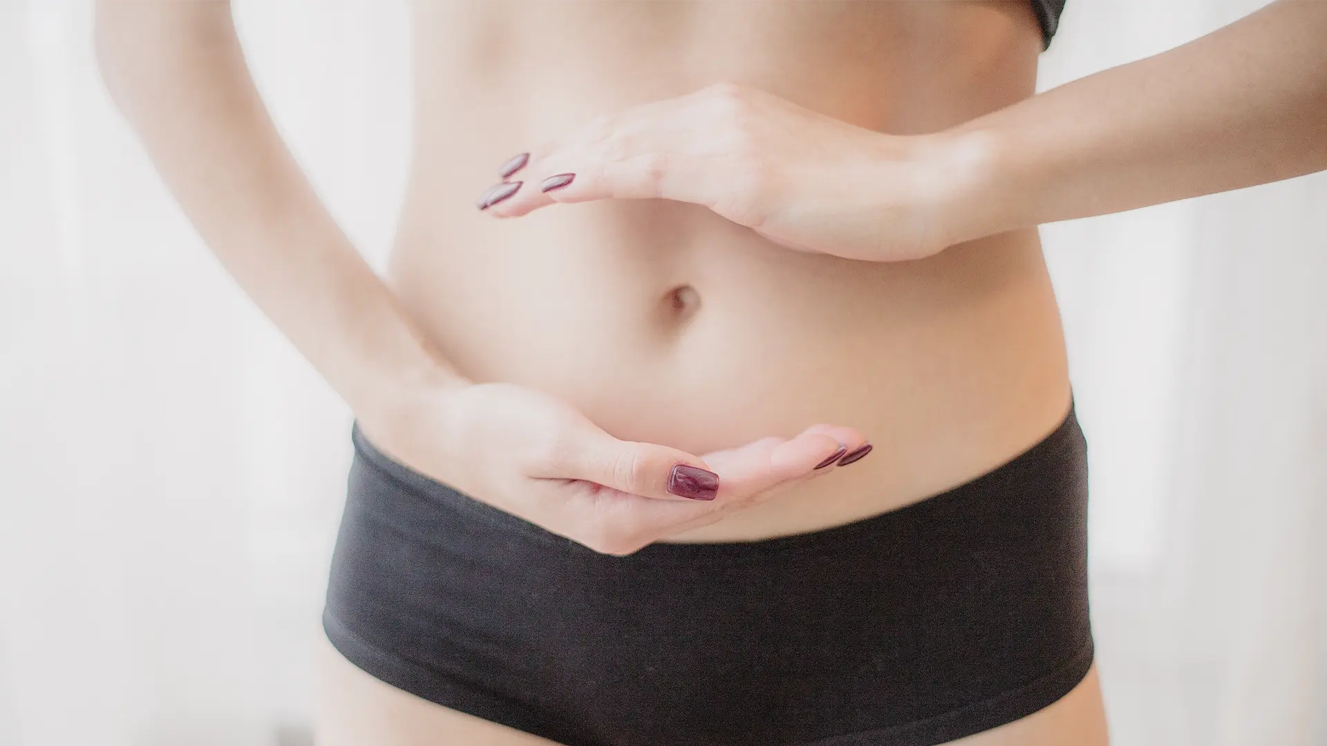 Hände einer Frau formen schützend einen Kreis auf ihrem Bauch – Symbolbild für Darmgesundheit, Verdauung und innere Balance.